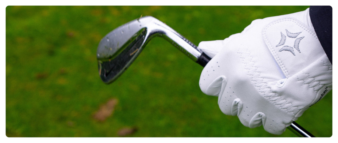 En bild på en vänster hand med en golfhandske på, i handen håller golfaren en golfklubba.